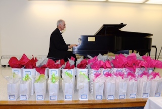 Richard Gagliano playing piano and scholarship gift bags lined up